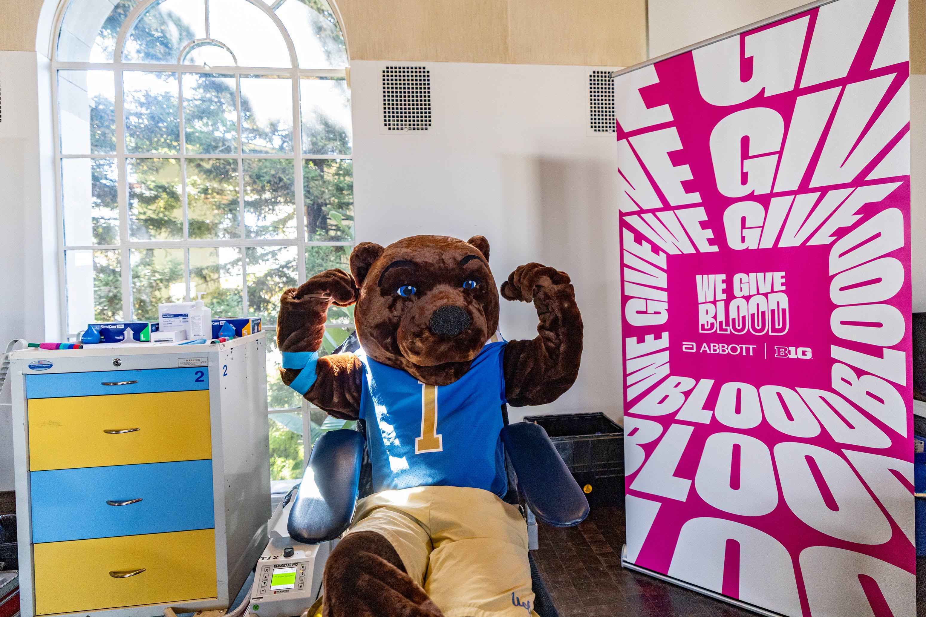 Joe Bruin sits near announcement of We Give Blood Drive